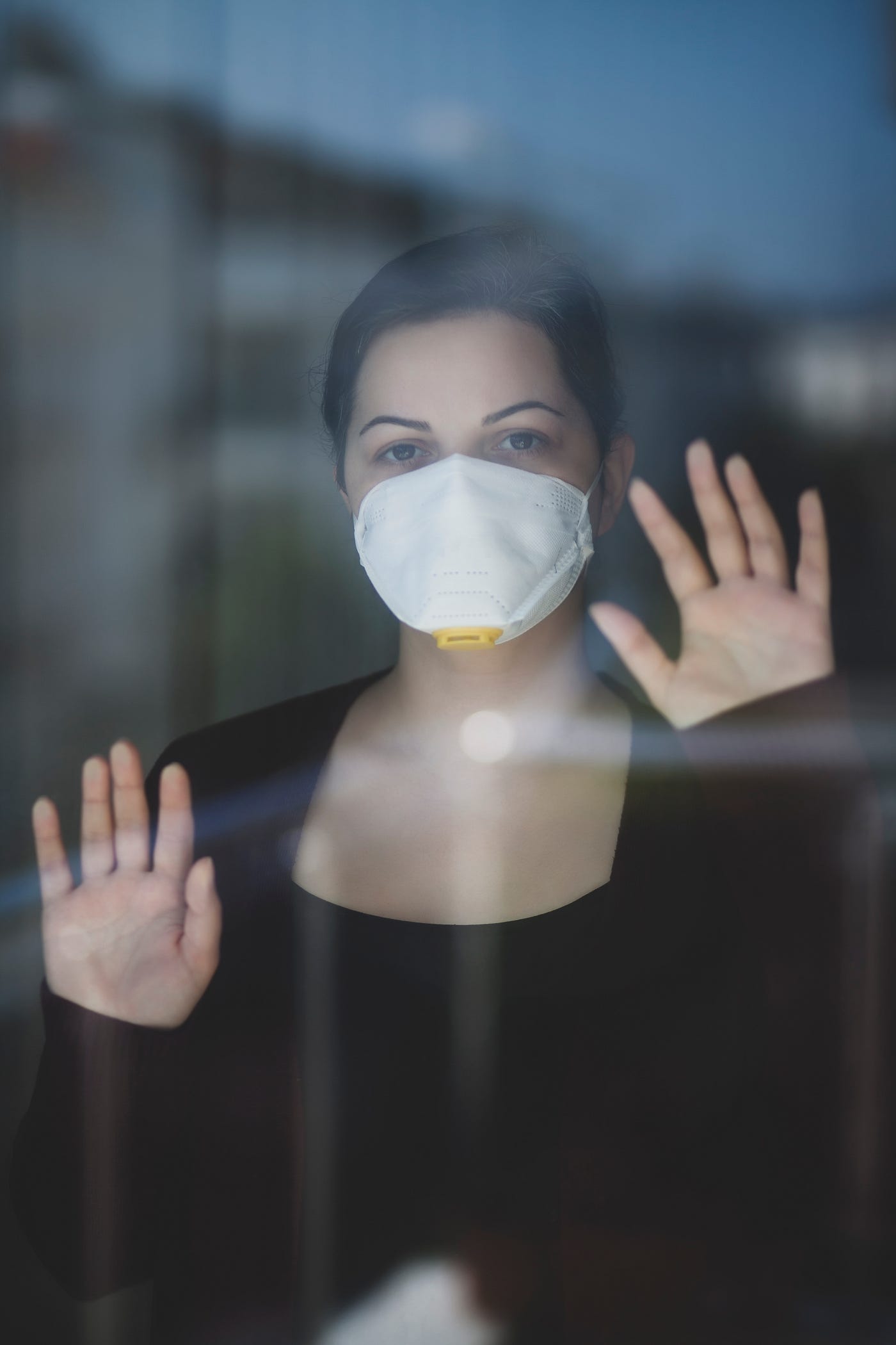 A woman in a mask isolated behind glass.